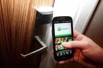 A person using a Samsung Galaxy S3 smartphone to open a door at the Olympic Games experience venue, utilizing the Holiday Inn app.