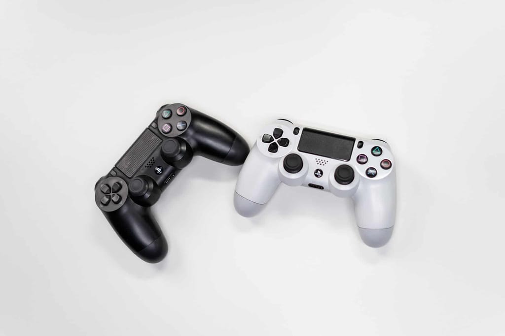 A black and a white video game controller on a plain white background.